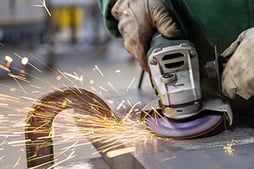 An operator removes mill scale from a workpiece with a bonded grinding wheel. These wheels are more aggressive and leave the material with a rough surface.